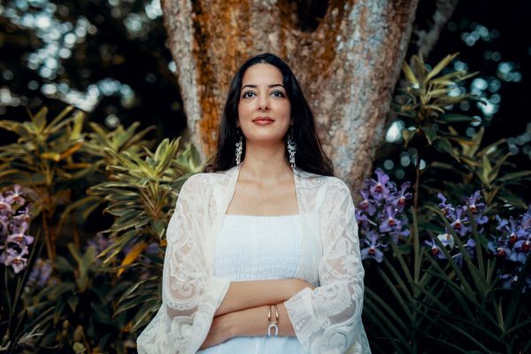 Zeeba Khan sitting in front of tree with tropical plants and flowers